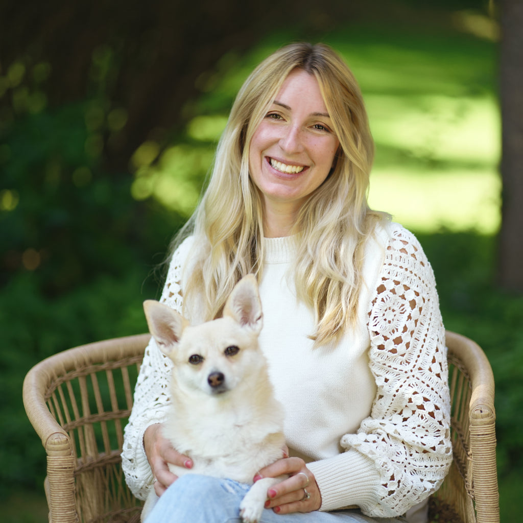 Author and illustrator Caroline Kerfoot sitting outdoors with a the IRL Fox the dog, smiling.