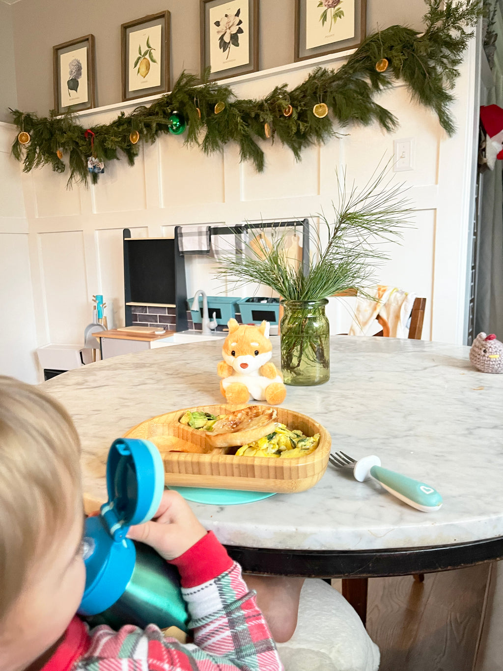 Child having breakfast with Fox the dog plush toy at a table in a home setting.